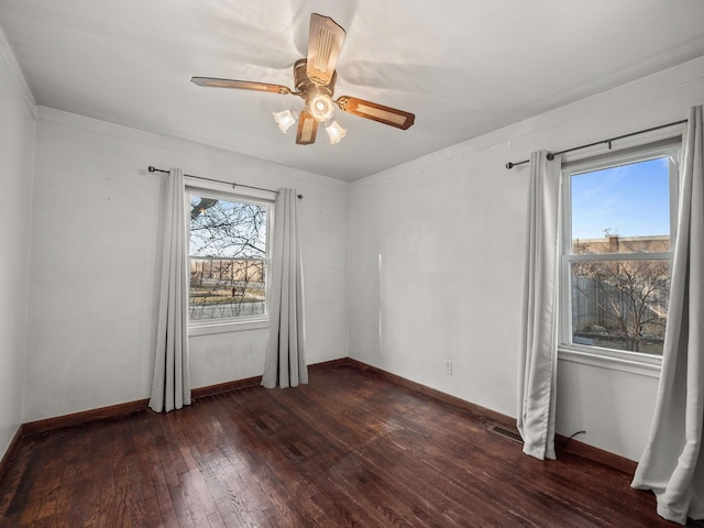 spare room featuring a wealth of natural light, baseboards, ceiling fan, and dark wood-style flooring