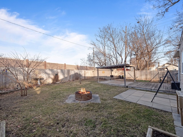 view of yard featuring a wooden deck, a fire pit, and a fenced backyard