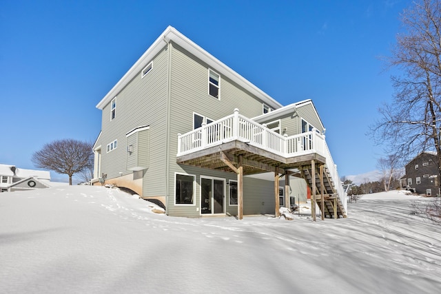 snow covered back of property featuring a deck and stairway