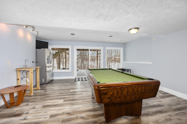 game room featuring a textured ceiling, a sink, wood finished floors, and baseboards