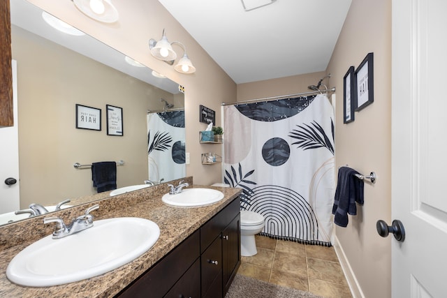 full bathroom featuring double vanity, a sink, toilet, and baseboards