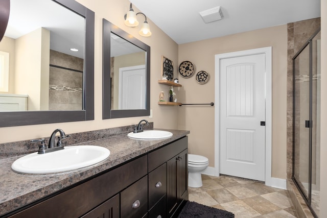 bathroom featuring double vanity, a sink, toilet, and a shower stall