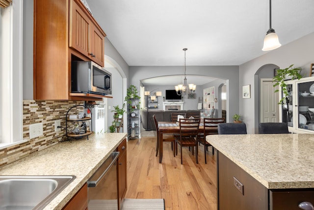 kitchen featuring light wood-style flooring, stainless steel appliances, light countertops, and decorative light fixtures