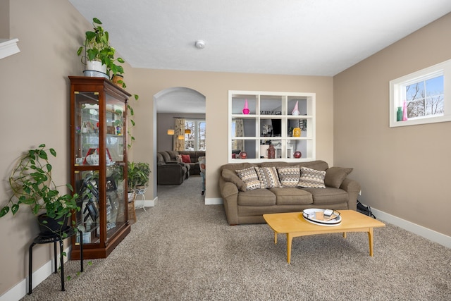 living room with arched walkways, carpet floors, and baseboards