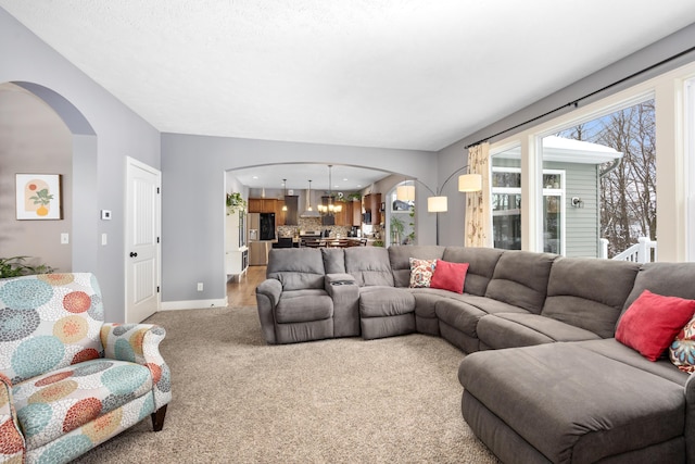 living room with arched walkways, baseboards, a chandelier, and light colored carpet