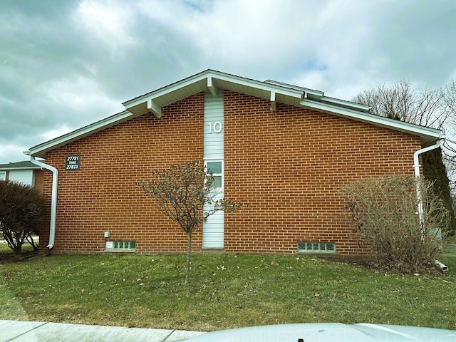 view of side of property featuring brick siding and a lawn