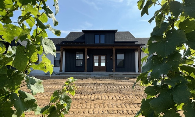 back of property with board and batten siding, french doors, and covered porch