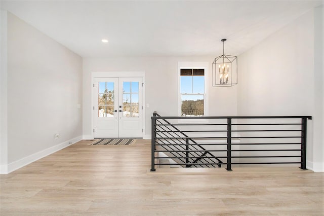 foyer with french doors, a notable chandelier, recessed lighting, wood finished floors, and baseboards