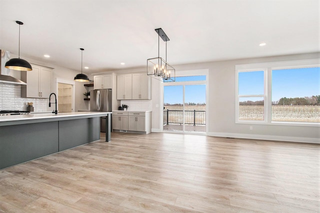 kitchen with light wood-style floors, pendant lighting, light countertops, and backsplash