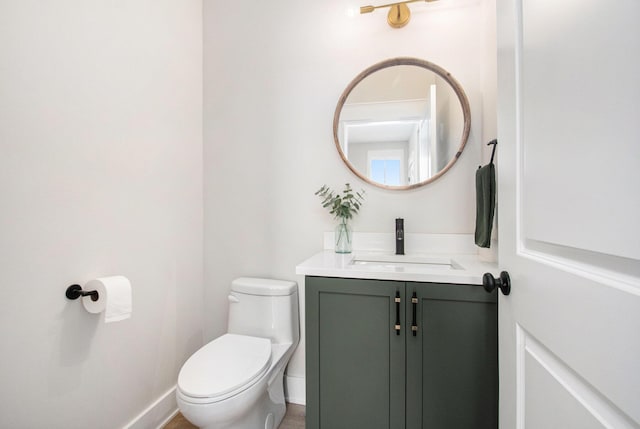 half bath featuring vanity, toilet, and baseboards