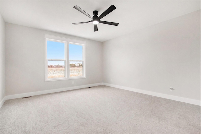 unfurnished room with a ceiling fan, light colored carpet, visible vents, and baseboards