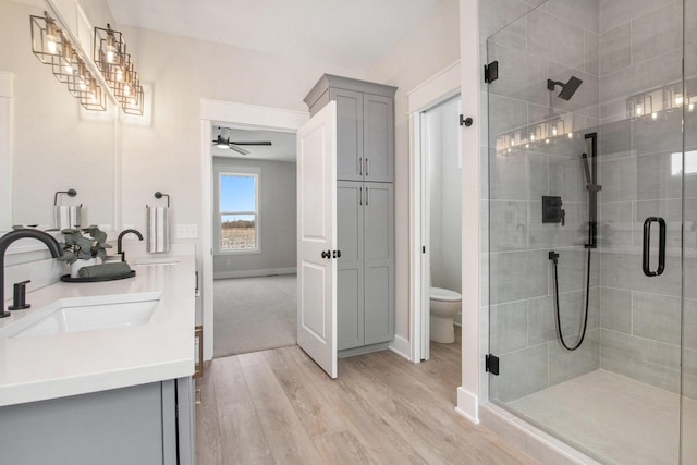 full bathroom featuring toilet, a stall shower, a sink, and wood finished floors