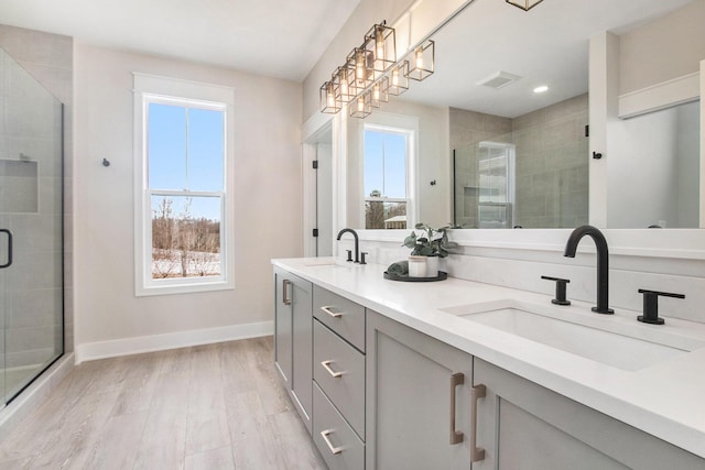 full bath featuring visible vents, a sink, a shower stall, and wood finished floors