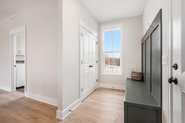 interior space with washer / clothes dryer, light wood-type flooring, visible vents, and baseboards