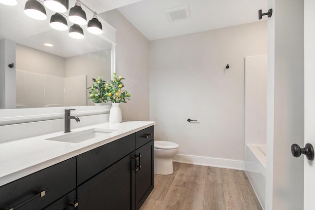 bathroom featuring toilet, wood finished floors, vanity, visible vents, and baseboards