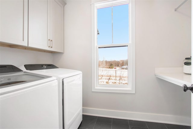 clothes washing area featuring dark tile patterned floors, washing machine and clothes dryer, cabinet space, and baseboards