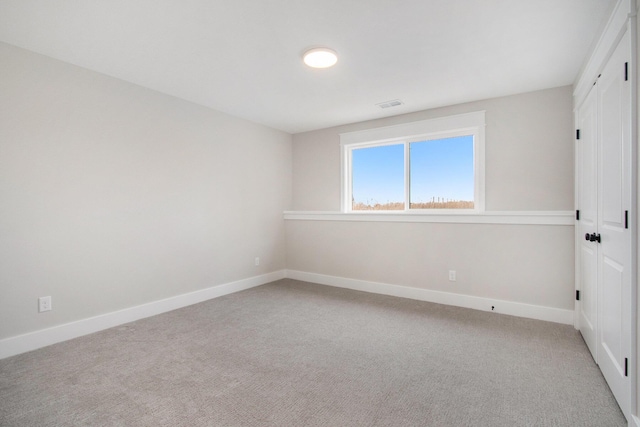 empty room with light colored carpet, visible vents, and baseboards