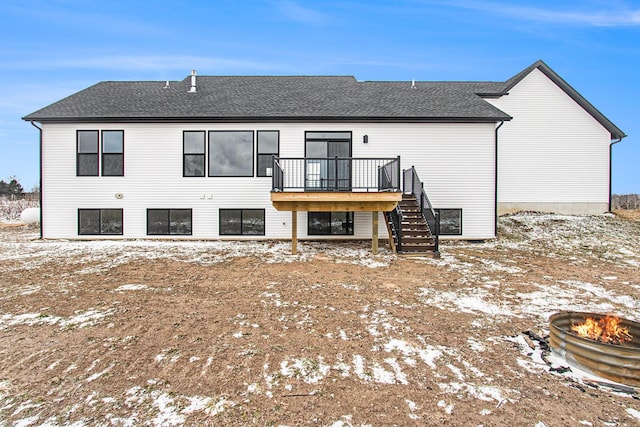 snow covered property with stairway, roof with shingles, a fire pit, and a wooden deck