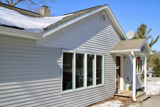 view of side of home with roof with shingles and a chimney