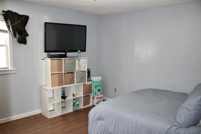 bedroom featuring a textured ceiling, baseboards, and wood finished floors