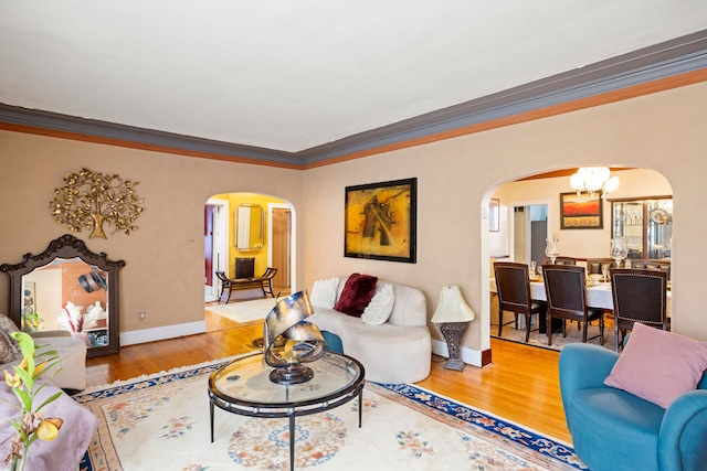 living room featuring arched walkways, baseboards, wood finished floors, and a notable chandelier