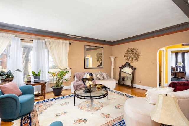 living room with baseboards, arched walkways, wood finished floors, and crown molding