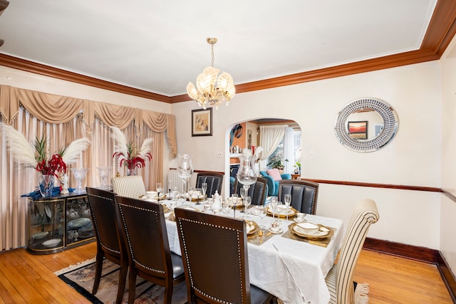 dining area featuring ornamental molding, arched walkways, hardwood / wood-style floors, and an inviting chandelier