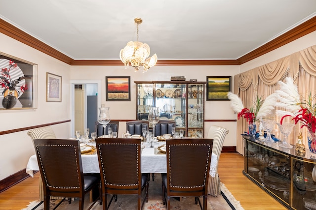 dining space featuring ornamental molding, baseboards, an inviting chandelier, and wood finished floors