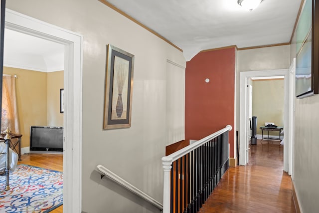 hall featuring wood finished floors, an upstairs landing, and crown molding