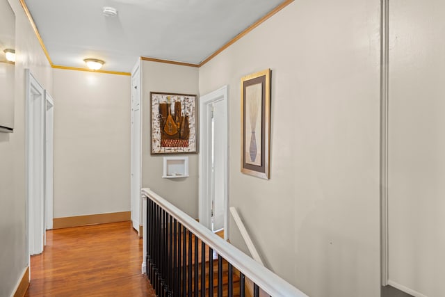 hallway featuring ornamental molding, wood finished floors, an upstairs landing, and baseboards