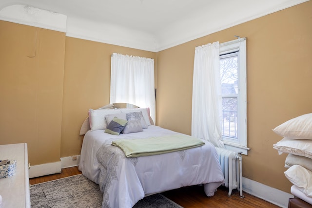 bedroom featuring baseboards, wood finished floors, and radiator