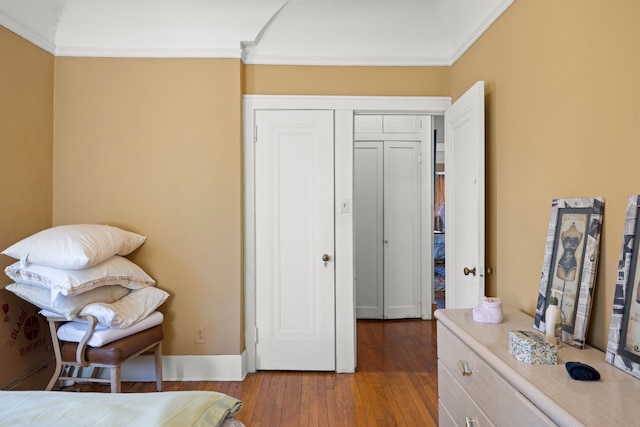 bedroom featuring ornamental molding, baseboards, and wood finished floors