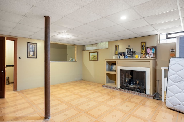 basement with a brick fireplace, a drop ceiling, and recessed lighting