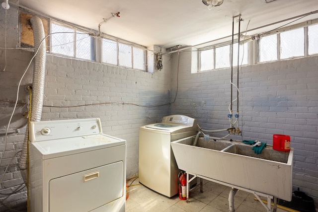 laundry area featuring laundry area, a sink, brick wall, and separate washer and dryer