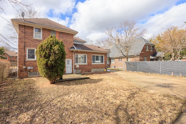 rear view of house featuring brick siding and fence