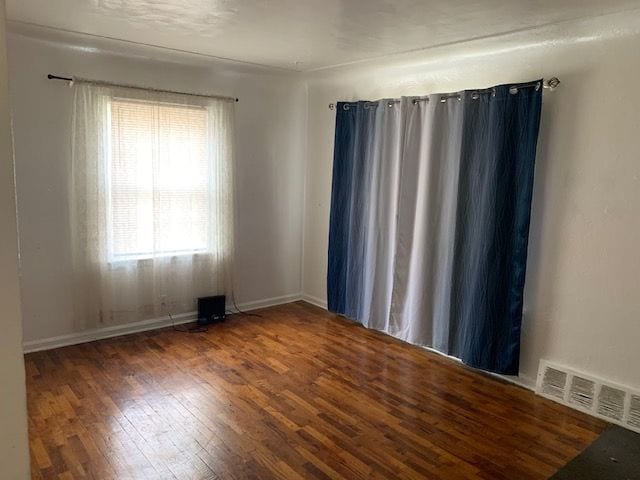 spare room with baseboards, visible vents, and hardwood / wood-style floors