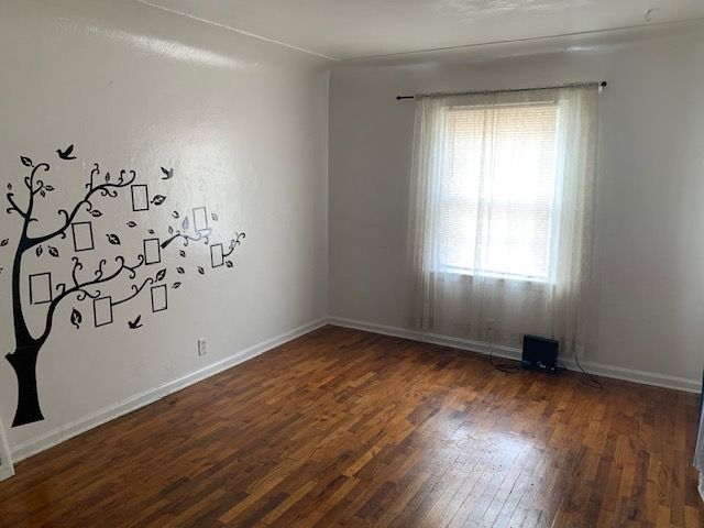 spare room with baseboards and hardwood / wood-style floors