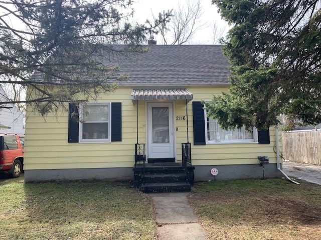 bungalow featuring entry steps, a shingled roof, fence, and a front yard