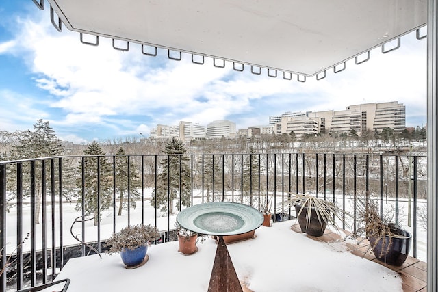 snow covered back of property featuring a view of city