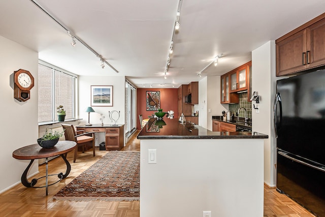 kitchen featuring dark countertops, decorative backsplash, glass insert cabinets, freestanding refrigerator, and a kitchen island