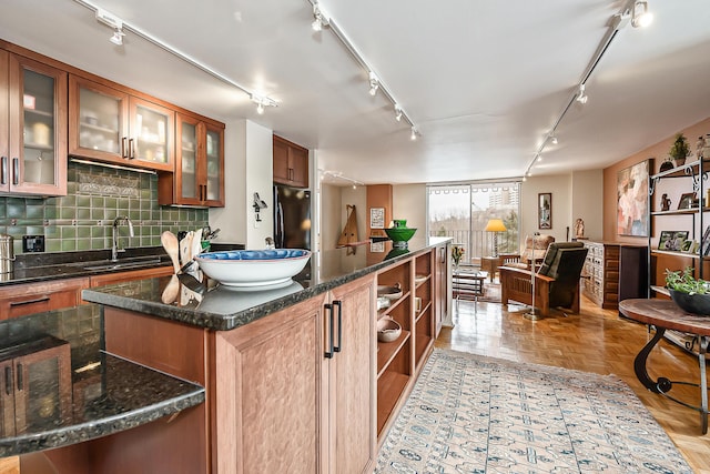 kitchen featuring a kitchen island, black refrigerator, a sink, rail lighting, and backsplash