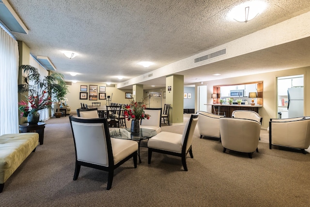 carpeted dining room featuring visible vents and a textured ceiling