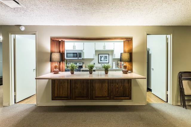 kitchen featuring light carpet, visible vents, stainless steel appliances, and a textured ceiling