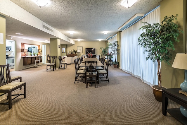 carpeted dining space featuring a textured ceiling and visible vents