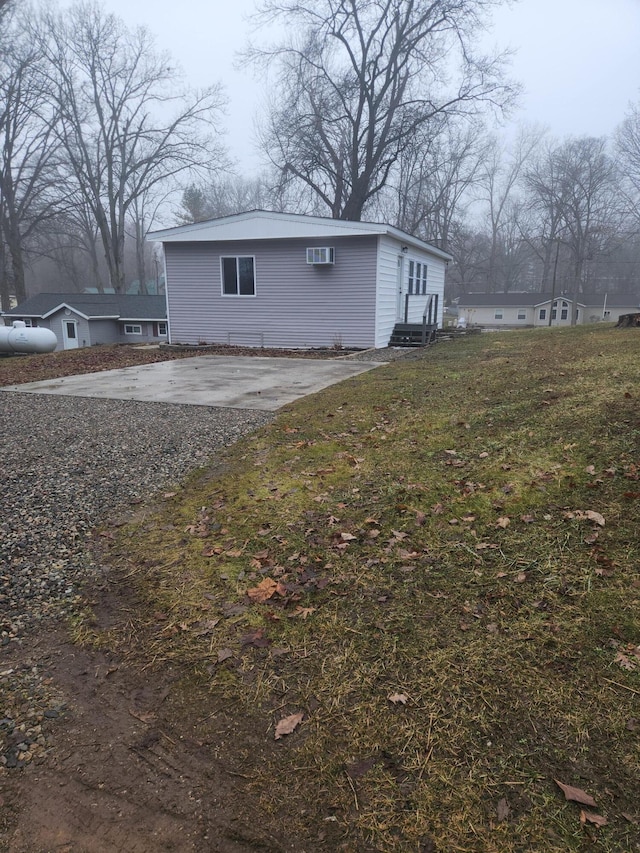 view of side of home with entry steps, concrete driveway, and a yard