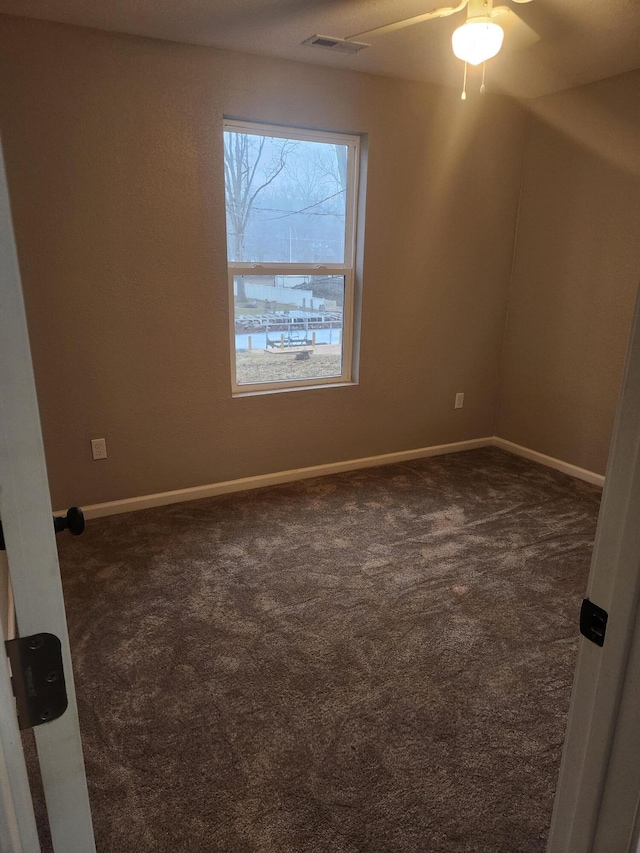 spare room featuring dark carpet, baseboards, and ceiling fan