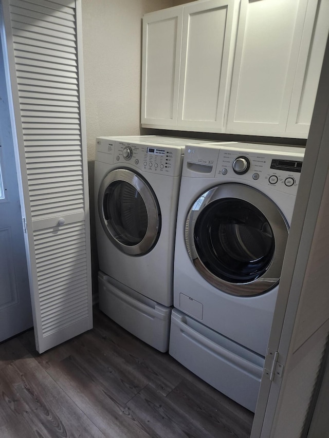 washroom featuring dark wood-type flooring, cabinet space, and washing machine and clothes dryer
