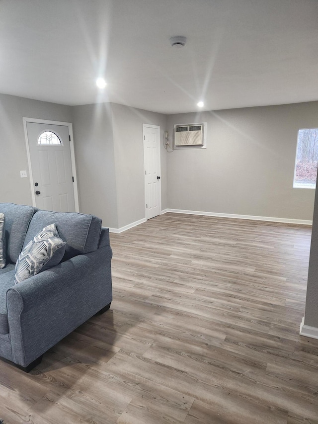living room featuring an AC wall unit, recessed lighting, wood finished floors, and baseboards
