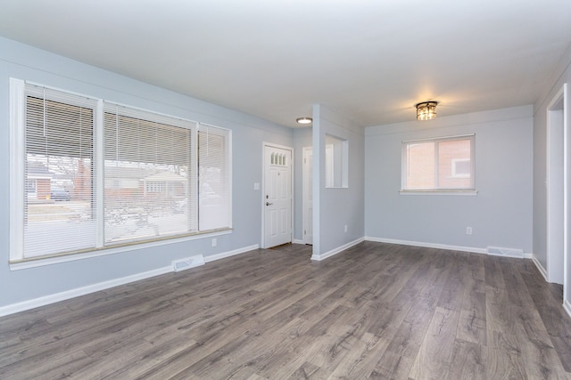 empty room featuring baseboards, visible vents, and dark wood-type flooring