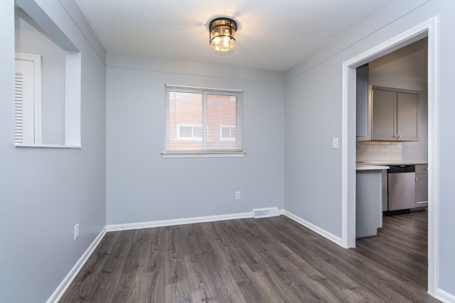 unfurnished room with dark wood finished floors, visible vents, and baseboards